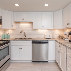 The kitchen features white cabinetry, granite countertops, and stainless appliances, creating a bright cooking space