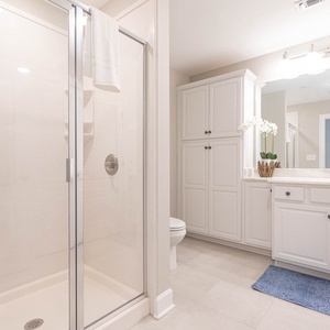 Enjoy a relaxing shower after a day at the beach in this guest bath with stylish accents and fluffy towels