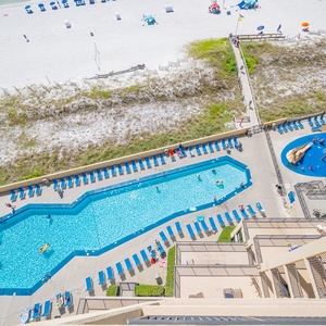 The pool area features a large, inviting pool surrounded by lounge chairs and a colorful pirate ship splash park