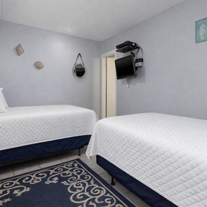 The guest bedroom features two cozy double beds, a charming dresser, and beach-themed decor for a relaxed getaway