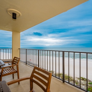 Relax on the private balcony with wooden seating, enjoying breathtaking views of the serene beach and tranquil waters