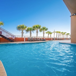 Take a swim in the pool with a waterslide, surrounded by palm trees and a stunning beachfront view just steps away