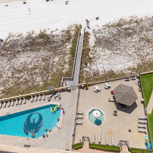 Aerial balcony view showcasing the vibrant pool area, a kiddie pool, and easy access to the white sand beach