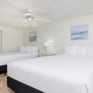 This guest bedroom features two queen beds, soft linens, and coastal artwork, creating a serene and inviting atmosphere