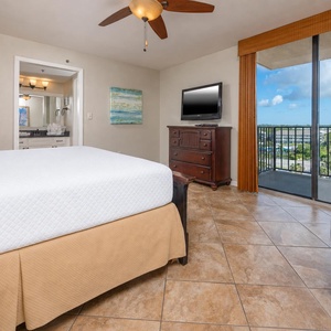 The master suite features a comfortable king bed, a flat-screen TV, and a lovely view from the balcony