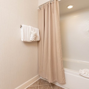 Refresh in the guest bath featuring a tub/shower combo, plush towels, and a well-lit space for your comfort