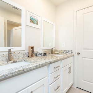 The master bathroom features a stylish double vanity with granite countertops, modern fixtures, and ample storage