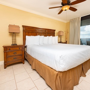 Master suite bedroom features a king bed, wooden furniture, and access to a balcony with views of the beach