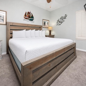 Cozy bedroom featuring a king bed with plush white linens, a bedside lamp, and a mounted TV for entertainment