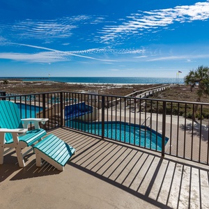 Relax in colorful chairs on the extended balcony, overlooking the pool and a scenic view of the coastline