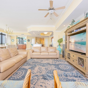 Living space featuring a cozy leather sofa, queen sofa-sleeper, large windows, and a stylish TV cabinet with beach decor