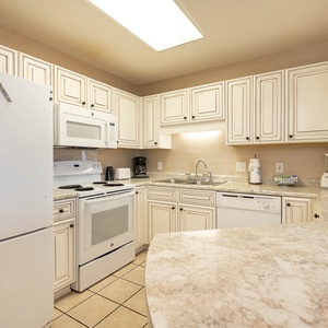 White cabinetry and granite countertops complement the modern kitchen, featuring essential appliances and ample workspace