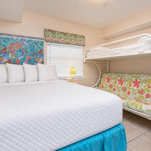This guest bedroom features a vibrant underwater mural, a queen bed, and a bunk bed, perfect for family stays