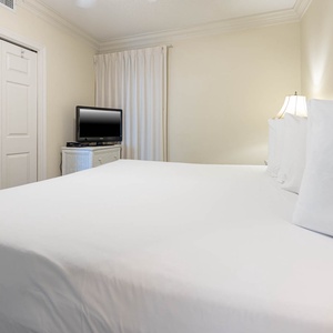 Bedroom featuring a king bed, a TV for entertainment, and soft lighting from bedside lamps, creating a relaxing vibe
