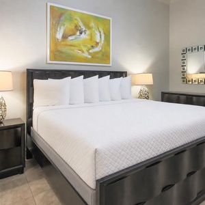 This guest bedroom features a king bed with plush pillows, elegant lamps, and vibrant artwork, creating a serene retreat