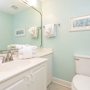 Aqua walls complement the spacious vanity area in the half bath adorned with fresh white towels and a decorative print