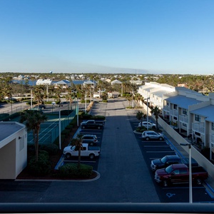 View of the surrounding area featuring palm trees, the tennis court, and view of the bay waters