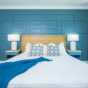 Stylish master bedroom with a plush king bed, decorative pillows, and soothing blue accents for a restful stay