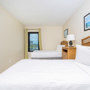 The guest bedroom features two comfortable beds, a charming nightstand, and a window view of the vibrant surroundings