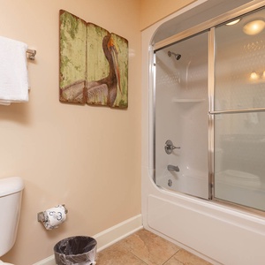 This bathroom features a sleek shower with glass doors, fresh white towels, and a charming bird artwork for a relaxing vibe