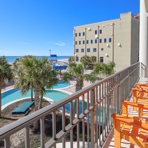 Relax on the balcony with vibrant orange chairs, overlooking the lazy river and the beautiful beachfront view