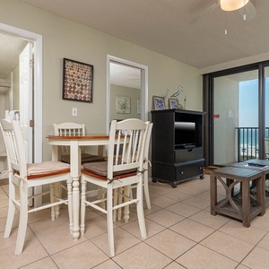 This cozy living area features a TV, a small dining table, and stunning beachfront views through large sliding glass doors
