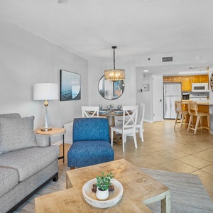 The inviting living area features a gray sofa, blue accent chair, and a dining space with a round table