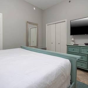 Brightly colored furniture adds to the serene atmosphere of this guest bedroom, featuring a king bed and a wall-mounted TV