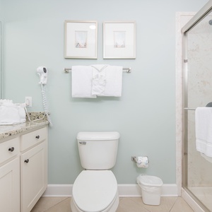 Enjoy a relaxing shower after a day at the beach in this guest bath with stylish accents and fluffy towels