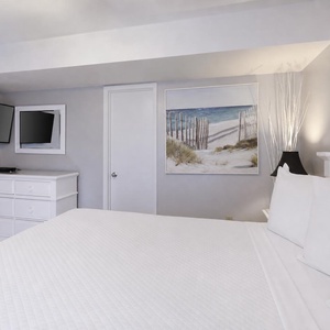 King suite featuring a cozy bed, TV, and beach-themed artwork for a relaxing retreat