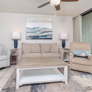 This inviting living area features a cozy sofa, stylish chairs, and a stunning beachfront view through large glass doors