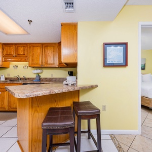 Bright kitchen featuring wooden cabinetry, a breakfast bar with seating, and a view into the master suite