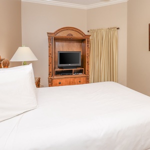 Relax in your comfortable queen bed while enjoying a movie in this guest room, adding cozy vibes to your retreat