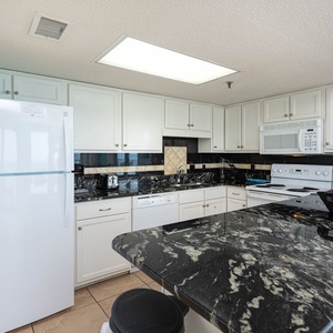 Kitchen featuring white cabinetry, black granite countertops, and essential appliances