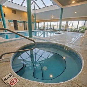 Soak in the inviting hot tub with a view of the indoor pool and lush greenery, unwind at Romar Place after a day of fun