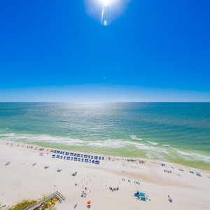 Coastal view with soft white sand and colorful beach umbrellas under a bright blue sky