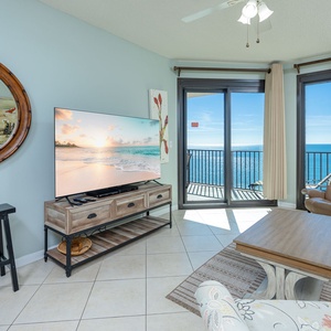 Relax in the inviting living area, featuring a large TV, comfortable seating, and stunning beach views