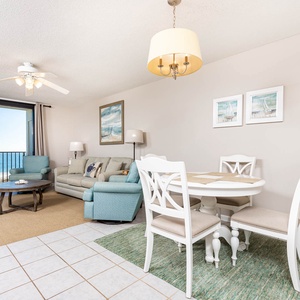 Cozy living area features a light sofa with queen sleeper, a round dining table, and a beautiful beachfront view