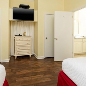 Cozy guest bedroom featuring double beds, a TV, and easy access to the bathroom area for your convenience