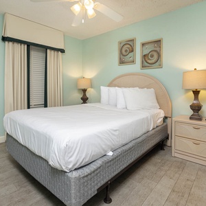 Rest in this tranquil guest bedroom featuring a comfortable queen bed, soft lighting, and coastal decor