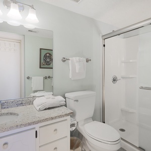 This bathroom features a stylish granite countertop, fresh towels, and a modern shower for a refreshing experience