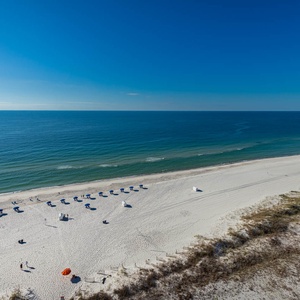 Gaze at the tranquil waters and enjoy the beach setup with umbrellas and chairs, perfect for a relaxing day
