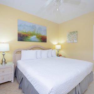 Brightly decorated bedroom featuring a king bed, bedside lamps, and artwork, creating a serene and inviting atmosphere