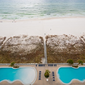 This view showcases the sparkling pool area with lounge chairs, leading to a pristine beach just steps away