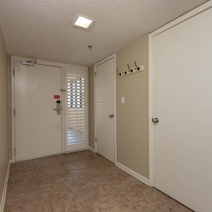 Welcoming entryway features tile flooring, a mirror, and hooks for convenience, leading to a bright balcony view