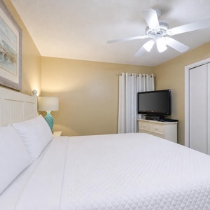 Relax in this cozy king suite featuring a plush bed, a TV, and soft lighting for a restful atmosphere