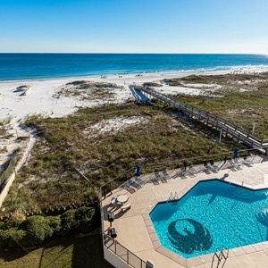 Stunning beachfront view reveals white sand and tranquil waters, with a pool area inviting relaxation under the sun