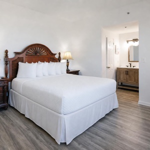 Master bedroom featuring a plush and wooden king bed, elegant lamps, and a stylish ensuite bathroom