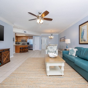 Inviting living space with a comfortable sofa with queen sleeper, large TV, and a view into the kitchen and dining area
