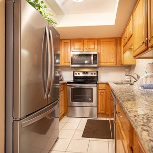 Modern kitchen with stainless appliances, warm wood cabinetry, and granite countertops, perfect for preparing meals